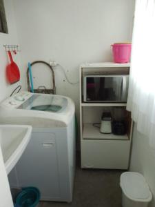 a small kitchen with a sink and a microwave at Apartamento Dona Frida Prainha com WiFi pé na areia in Caraguatatuba