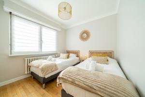 zwei Betten in einem Schlafzimmer mit Fenster in der Unterkunft La Maison Royale - Terrasse et Jardin in Haguenau