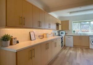 a large kitchen with white cabinets and a sink at Fern Cottage in Portinscale