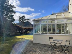 a glass house with two chairs and a table at Fern Cottage in Portinscale