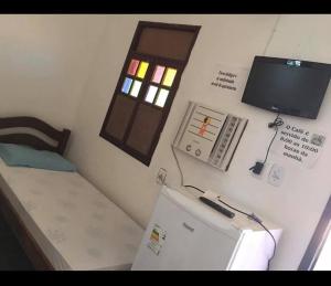 a small room with a small refrigerator and a window at Pousada subauma in Subaúma