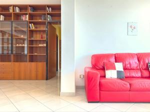 a red couch in a living room with a book shelf at Homeby, Casa Cartesio in Milan