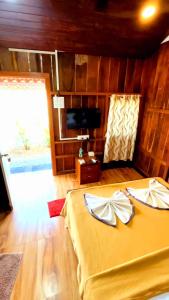 a bedroom with a yellow bed and a television at Mai's Beach Resort in Malvan