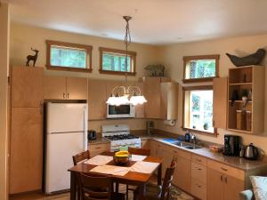 a kitchen with a table and a white refrigerator at The Bungalow -- Minutes from the Airport - on the Way to the Glacier in Juneau