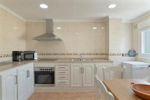 una cucina con mobili bianchi, un lavandino e un tavolo di Céntrico apartamento en Tarifa a Tarifa