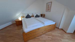 a bedroom with a wooden bed with white sheets at Residenz am Deich NDD 28 in Norden
