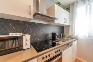 a kitchen with a stove and a microwave at GREAT PLACE Top Penthouse Stuttgart Airport & Messe in Filderstadt