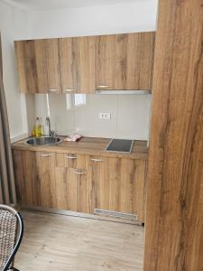 a kitchen with wooden cabinets and a sink at GREJM Family Apartments in Petrovac na Moru