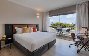 a hotel room with a bed and a large window at Kfar Maccabiah Business & Sport Hotel in Ramat Gan