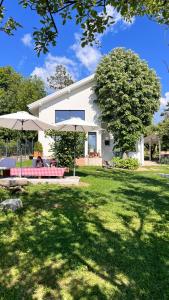 a house with a table and two umbrellas in a yard at Vila blizu Beograda - My Family Cottage in Ba°evac