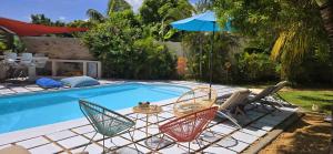 a pool with chairs and a table and an umbrella at LAKAZ DEL SOL - Elegant apartments with luxurious garden, pool and barbecue area - Tourism Permit Certified in Tamarin