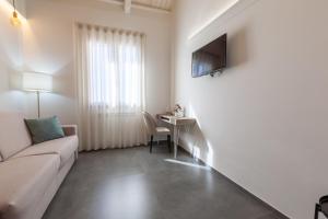 a white living room with a couch and a table at Oneira Rooms in Agrigento