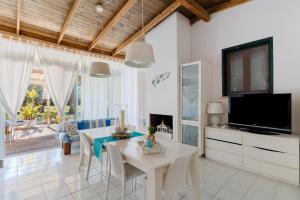 a dining room with a white table and a tv at Deliziosa Villa Patrizia a Otranto in Otranto