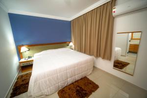 a bedroom with a white bed and a mirror at Hotel Dan Inn Sorocaba by Nacional Inn in Sorocaba
