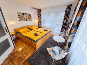 a bedroom with a yellow bed and a table and chairs at Iskolakert Apartman in Sárospatak