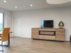 a living room with a tv on a wooden dresser at Luxuriöse, große Wohnung mit Parkblick in Mettmann
