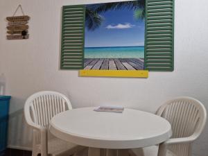 a white table and chairs with a picture of the ocean at Gwada paradise, marina du gosier in Le Gosier