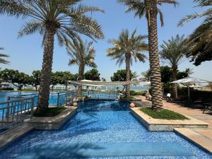 a swimming pool with palm trees in a resort at Bright 2 Bedroom Apartment, Beach & Pool Access in Dubai