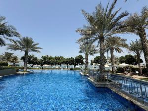 a swimming pool with palm trees in a resort at Bright 2 Bedroom Apartment, Beach & Pool Access in Dubai