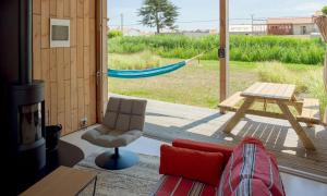 ein Wohnzimmer mit einem Sofa und einer Hängematte auf einer Veranda in der Unterkunft LA FERME DU MARAIS GIRARD (Villas) in Brétignolles-sur-Mer