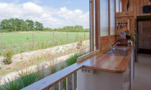 ein Bad mit einem Waschbecken und Blick auf ein Feld in der Unterkunft LA FERME DU MARAIS GIRARD (Villas) in Brétignolles-sur-Mer