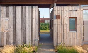 ein Holzgebäude mit einem Flur, der zu einer Tür führt in der Unterkunft LA FERME DU MARAIS GIRARD (Villas) in Brétignolles-sur-Mer
