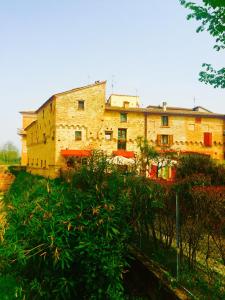 un gran edificio de ladrillo con sombrillas rojas delante de él en Locanda Delle Fate, en San Giovanni in Marignano