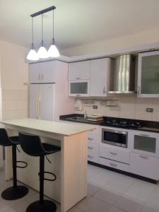 eine Küche mit weißen Schränken und eine Insel mit Barhockern in der Unterkunft Comodidad y relax en Apartamento cerca del mar en Chichiriviche in Chichiriviche