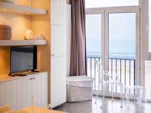 Una sala de estar con televisión y un balcón. en Apartment on the Coast with Beach Access, en Oostduinkerke