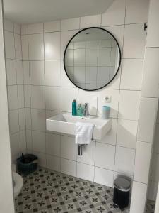 a white tiled bathroom with a sink and a mirror at Het Doktershuys in Gieten