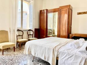 Un dormitorio con una cama y dos sillas y un espejo. en Dimora storica con accesso privato alla spiaggia - Villa Drei, en Rímini
