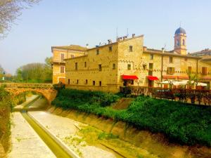 ein großes Gebäude neben einem Fluss mit einer Brücke in der Unterkunft Locanda Delle Fate in San Giovanni in Marignano