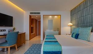 a hotel room with a bed and a desk and a television at The Park Visakhapatnam in Visakhapatnam