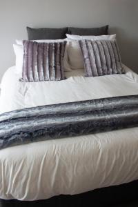 a large bed with white sheets and pillows at Annebella's in Gordonʼs Bay