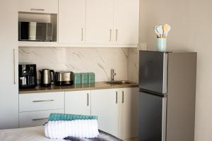 a kitchen with white cabinets and a refrigerator at Annebella's in Gordonʼs Bay