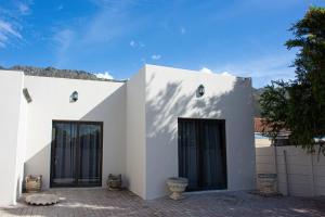 a white house with black doors and a fence at Annebella's in Gordonʼs Bay