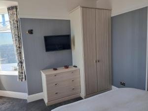 a bedroom with a bed and a dresser with a television at Eddystone Light Apartment in Mevagissey