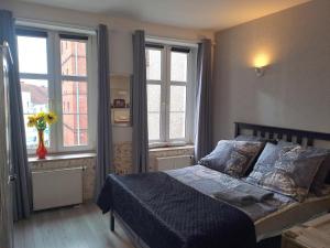 een slaapkamer met een bed en twee ramen bij Stare Miasto in Olsztyn