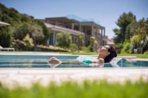 a woman laying in a swimming pool at Chia Laguna - Hotel Village in Chia