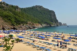 a beach with many umbrellas and chairs and the ocean at Kleopatra Atlas Hotel - Adults Only in Alanya