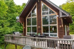 a log cabin with large windows and a deck at Carriole - Private Hot Tub - Hiking and Skiing in Val-des-Lacs