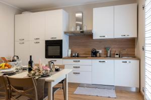a kitchen with white cabinets and a table with flowers at Casa Belfiore, Darfo Boario Terme Ospitar in Boario Terme +25 photos
