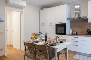 a kitchen with a table and chairs and a kitchen with white cabinets at Casa Belfiore, Darfo Boario Terme Ospitar in Boario Terme