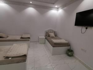 a room with two beds and a flat screen tv at شقق النبلاء in Al Madinah +24 photos