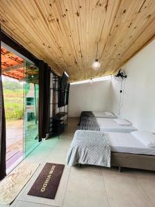 due letti in una stanza con soffitti in legno di Hospedaria Paraíso das Águas Suíte independente KitBet com cozinha completa a Itabirito