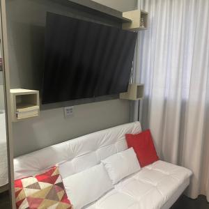 a white couch with two pillows and a flat screen tv at THE ONE - Flat Batel Premium in Curitiba +63 photos