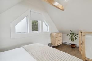 ein weißes Schlafzimmer mit einem Bett und zwei Fenstern in der Unterkunft Harbour View Loft at Bells Cove in Shelburne
