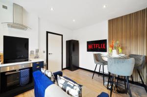 a living room with a blue couch and a tv at Boutique Penthouse in Yorkshire - Top Floor in Castleford