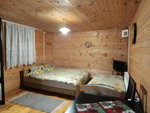 a bedroom with two beds in a wooden cabin at Seosko turisticko Domaćinstvo Radivojević in Kraljevo