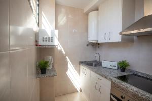 a kitchen with white cabinets and a sink at Dynastic Rooms Apartments in Benidorm